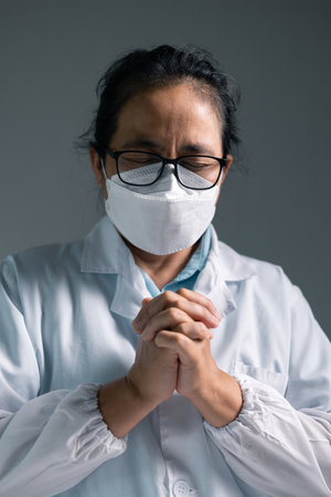 Doctor clasped their hands in prayer, hoping for the best as they provided medical care in hospital clinic. doctor, pray, medicine, health, medical, hand, hospital, care, clinic, hope, prayer, person.の写真素材