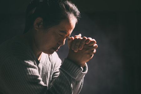 Woman clasped her hands in prayer, filled with faith and hope, believing in Jesus Christ, and seeking the holy presence of God through her prayers in the spirit of Christian religion. pray, woman.の写真素材