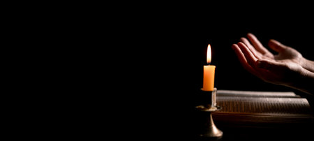 In the dark, hand clasped in prayer, illuminated by the soft candlelight, as black flames of candle fire flickered gently. candle, pray, hand, prayer, black, fire, flames, candlelight, light, dark.の写真素材