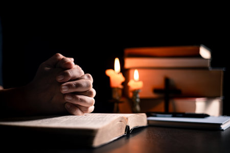 In the church, candle flickered beside cross as Christians gathered to pray, their faith in Jesus and spiritual devotion illuminated by Bible in background, deepening their Catholic worship.の写真素材