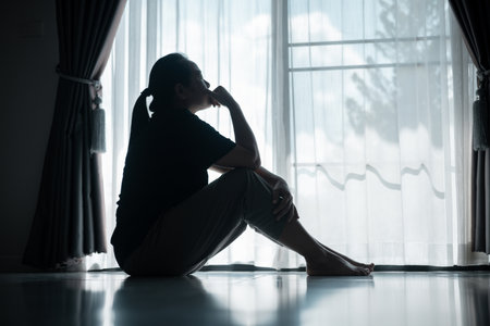 young woman sat alone, feeling weight of anxiety, stress, and depression, her sadness echoing struggles many people face in silence. anxiety, stress, depression, woman, person, sad, adult, alone.の写真素材