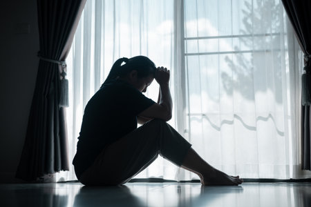 young woman sat alone, feeling weight of anxiety, stress, and depression, her sadness echoing struggles many people face in silence. anxiety, stress, depression, woman, person, sad, adult, alone.の写真素材