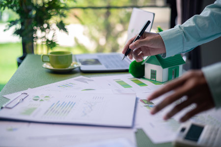 Analyzing green building performance metrics during business meeting. data analysis, green building, business meeting, sustainability, performance metrics, charts, graphs, real estate, eco-friendly.の写真素材