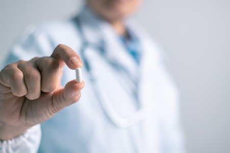 Doctor office, woman held medical capsule in her hand, illustrating role of medicine and pills in health care and overall health. woman, office, doctor, health, medical, capsule, pill, medicine.の写真素材