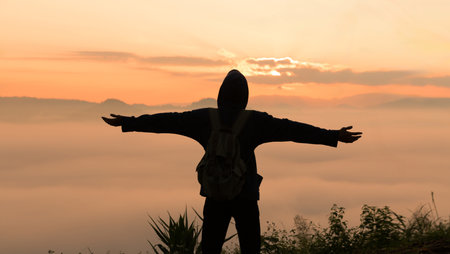 Man embarks on hiking adventure, traveling through mountain landscape at sunrise, enjoying serene morning sky and beauty of nature. mountain, person, travel, hiking, sunrise, adventure, nature.の写真素材