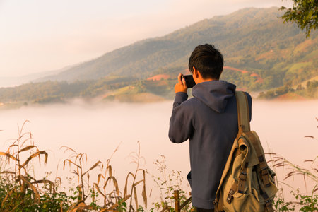 Man embarks on hiking adventure, traveling through mountain landscape at sunrise, enjoying serene morning sky and beauty of nature. mountain, person, travel, hiking, sunrise, adventure, nature.の写真素材