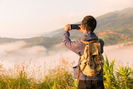 Man embarks on hiking adventure, traveling through mountain landscape at sunrise, enjoying serene morning sky and beauty of nature. mountain, person, travel, hiking, sunrise, adventure, nature.の写真素材