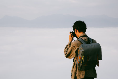 Man traveler with camera backpack hiking outdoor travel lifestyle and adventure concept. cap backpack and join of tourist for green mountain tour, beauty of nature and expansive sky people of tourismの写真素材