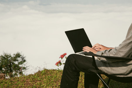 Young business man working computer on peak hill. Hiker online shopping on laptop at sunset, sunrise on top mountain, freelance person remote work with digital tablet. travel vacation holiday conceptの写真素材