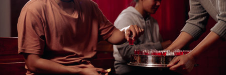 Close up of hands participating in a religious ceremony with spiritual faith on a holy text in a church setting. People are seen worshiping, praying, and asking for blessings with grace, believing in their faith.の写真素材