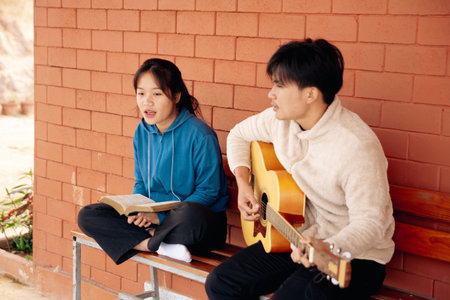 young woman reading bible with young man playing guitarの写真素材