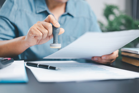 Businessman hands stamp approve on financial business approval document paper. Man hand accepted permit contract agreement. Broker manager sign contract bank guarantee approved stamp application formの写真素材