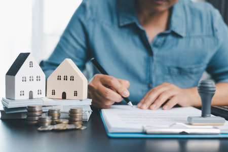 Female real estate broker presenting and advised to model home, building project detail in office, sign purchase sales application contract, agreements concerned mortgage loan offer and insurance.の写真素材