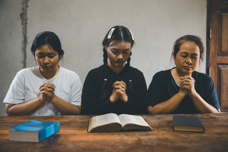 Praying religion, worship and group of people pray to God, Family, holding hands and prayer in home for love, support and faith or hope in house. holy spirit or Jesus for peace or spiritual praise.の写真素材