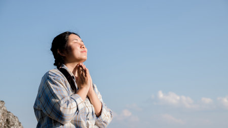 Grateful woman having HOPE praying to God. Spiritual girl smiling to sky. Happy female being thankful. Spiritual girl praying with hope. Positive Asian young woman feeling hope and faith looking up.の写真素材