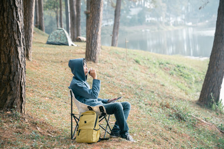 Remote work technology online close up communication smart phone laptop telephone digital travel brown nature sunlight camp beverage morning sit drink coffee tent orange outlying concept background.の写真素材