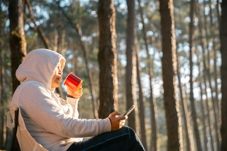 Remote work technology online close up communication smart phone laptop telephone digital travel brown nature sunlight camp beverage morning sit drink coffee tent orange outlying concept background.の写真素材