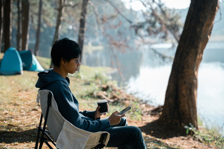 Remote work technology online close up communication smart phone laptop telephone digital travel brown nature sunlight camp beverage morning sit drink coffee tent orange outlying concept background.の写真素材