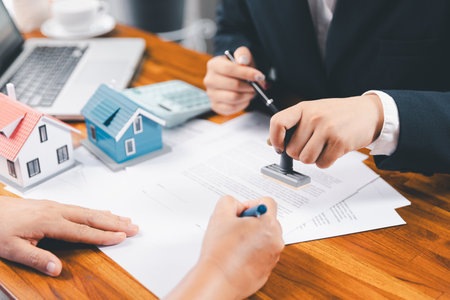 Bank approve loan to buy home concept. Real estate agent talked about terms of home purchase agreement, asked customer to sign documents to make contract legally. approved mortgage application form.の写真素材