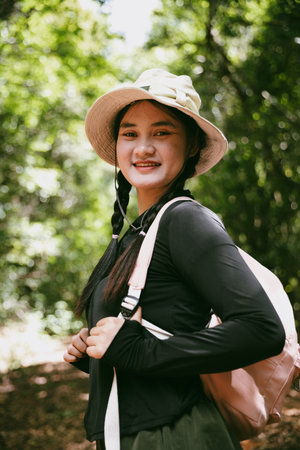 Young female traveler with backpack walking in national park or forest. recreation sport in nature. Female person bag, wave for hiking journey in woods. adventure in forest. trekking with backpackの写真素材