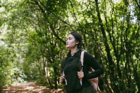 Young female traveler with backpack walking in national park or forest. recreation sport in nature. Female person bag, wave for hiking journey in woods. adventure in forest. trekking with backpackの写真素材