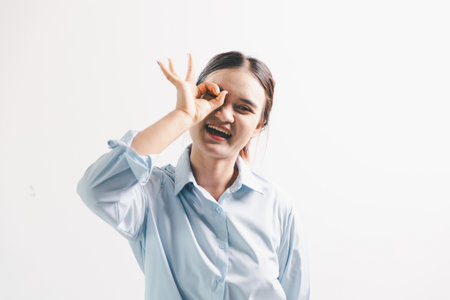 Asian woman rejoicing, looking happy, champion, fist pump gesture, standing over white background. young woman had happy, positive expression on her face, highlighted by bright smile.の写真素材