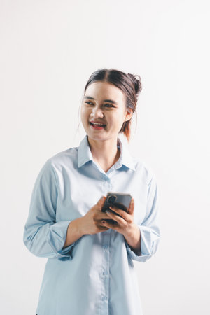 Asian woman rejoicing, looking happy, champion, fist pump gesture, standing over white background. young woman had happy, positive expression on her face, highlighted by bright smile.の写真素材