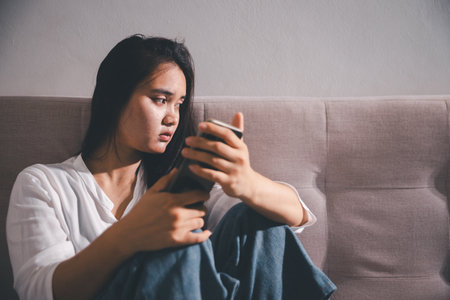 Sorrowful woman sat alone, overwhelmed by emotion, her sad and unhappy expression revealing deep despair, stress and distress left feeling depressed. sorrowful sad, despair alone, depressed stressの写真素材