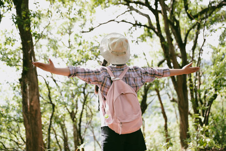 Young female traveler with backpack walking in national park or forest. recreation sport in nature. Female person bag, wave for hiking journey in woods. adventure in forest. trekking with backpackの写真素材