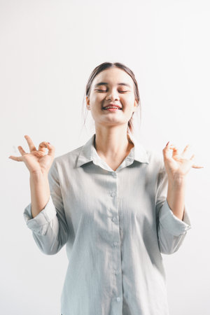 Asian woman rejoicing, looking happy, champion, fist pump gesture, standing over white background. young woman had happy, positive expression on her face, highlighted by bright smile.の写真素材