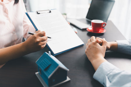 Woman real estate sale agent, client after signing agreement contract real estate with approved mortgage application form concerning mortgage loan offer, house insurance. contract agreement in officeの写真素材