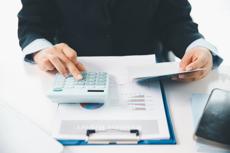 Business hands holding saving account passbook with calculator, account and saving concept. finance effectively, calculate income, track each bill and payment, accounting for bank statements and tax.の写真素材