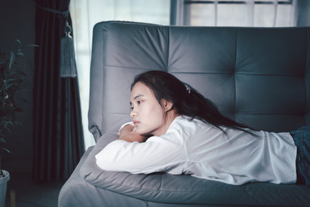 Sorrowful woman sat alone, overwhelmed by emotion, her sad and unhappy expression revealing deep despair, stress and distress left feeling depressed. sorrowful sad, despair alone, depressed stressの写真素材