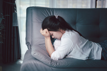 Sorrowful woman sat alone, overwhelmed by emotion, her sad and unhappy expression revealing deep despair, stress and distress left feeling depressed. sorrowful sad, despair alone, depressed stressの写真素材