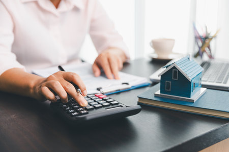 Calculator to check and summary expense of home loan mortgage for refinance plan , people lifestyle concept. Home agents are using calculator to calculate the loan period each month for customer.の写真素材