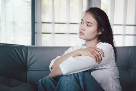 Sorrowful woman sat alone, overwhelmed by emotion, her sad and unhappy expression revealing deep despair, stress and distress left feeling depressed. sorrowful sad, despair alone, depressed stressの写真素材