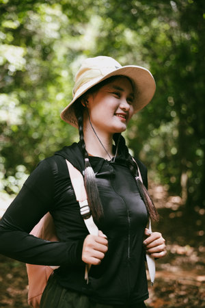 Young female traveler with backpack walking in national park or forest. recreation sport in nature. Female person bag, wave for hiking journey in woods. adventure in forest. trekking with backpackの写真素材