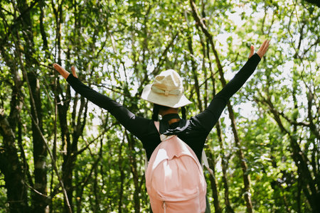 Young female traveler with backpack walking in national park or forest. recreation sport in nature. Female person bag, wave for hiking journey in woods. adventure in forest. trekking with backpackの写真素材