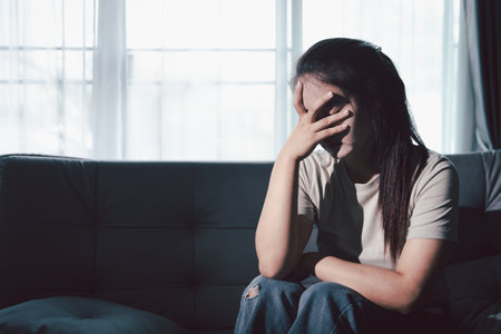 Despair sorrow person in empty dark room, Depressed young woman covering face with hands. Young woman coping with distress covering face. mental health concept. Boring sad upset frustrated stressed.の写真素材
