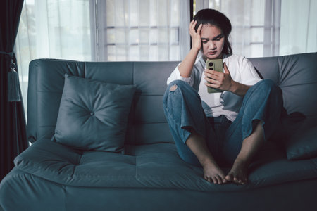 Sorrowful woman sat alone, overwhelmed by emotion, her sad and unhappy expression revealing deep despair, stress and distress left feeling depressed. sorrowful sad, despair alone, depressed stressの写真素材