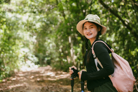 Young female traveler with backpack walking in national park or forest. recreation sport in nature. Female person bag, wave for hiking journey in woods. adventure in forest. trekking with backpackの写真素材