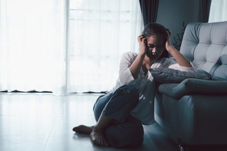 Tired depressed desperate tired girl sadly sitting on couch at home. Young woman is sitting on floor living room, feeling sad and depressed. Psychological problem. Depression and loneliness concept.の写真素材