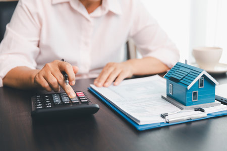 Calculator to check and summary expense of home loan mortgage for refinance plan , people lifestyle concept. Home agents are using calculator to calculate the loan period each month for customer.の写真素材