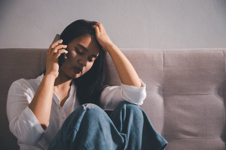 Sorrowful woman sat alone, overwhelmed by emotion, her sad and unhappy expression revealing deep despair, stress and distress left feeling depressed. sorrowful sad, despair alone, depressed stressの写真素材