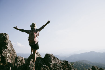 Woman hiker on top of mountain. Hiker with arms up on top of mountain successful young woman enjoying triumph. traveler exploring world. Hikers with backpacks relaxing. Sport and success concept.の写真素材