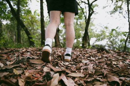 Hiking action on mountain grass trail path. Close up of female hiker shoe. adventurous lifestyle of hiker and backpack to travel and trek mountain, enjoy every walk and hike part of thrilling journeyの写真素材