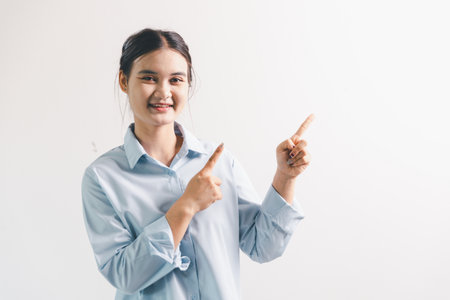 Asian woman rejoicing, looking happy, champion, fist pump gesture, standing over white background. young woman had happy, positive expression on her face, highlighted by bright smile.の写真素材
