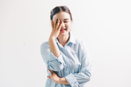 Asian woman rejoicing, looking happy, fist pump gesture, standing over white background. young woman had happy, positive expression on her face, highlighted by bright smile.の写真素材