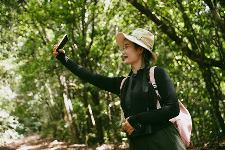 Young female traveler with backpack walking in national park or forest. recreation sport in nature. Female person bag, wave for hiking journey in woods. adventure in forest. trekking with backpackの写真素材