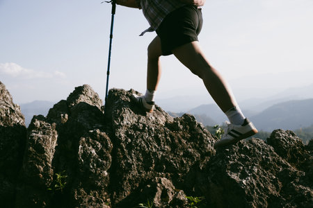 Hiking boot. Close up of female legs in boots on hiking trail on top of mountain outdoor. young woman reaching top of mountain. women feet wearing hiking boots on rock. Travel, vacation concept.の写真素材